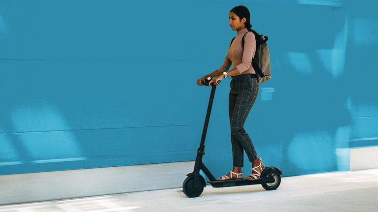 Young businesswoman riding an electric scooter