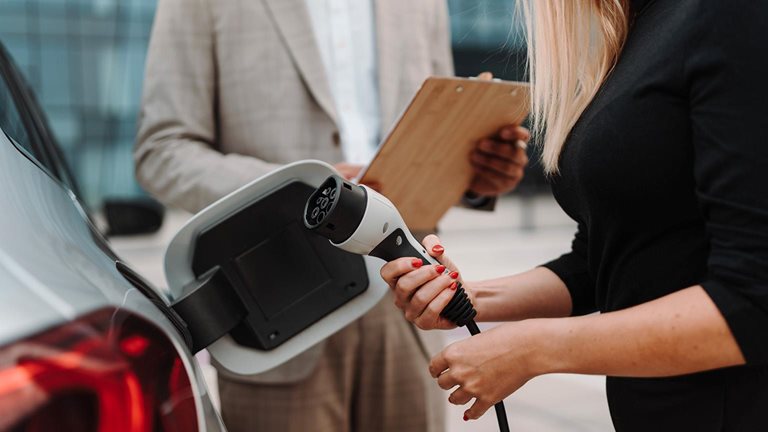 Young salesman showing charging electric car. - stock photo