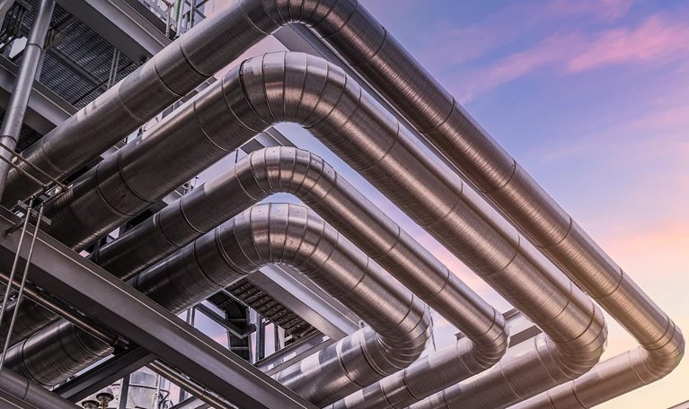 Steel pipelines and valves at at oil-refinery plant and sky - stock photo