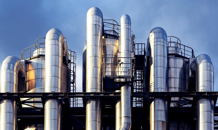 Image of interwoven chemical pipes at a factory shining in the sunset.