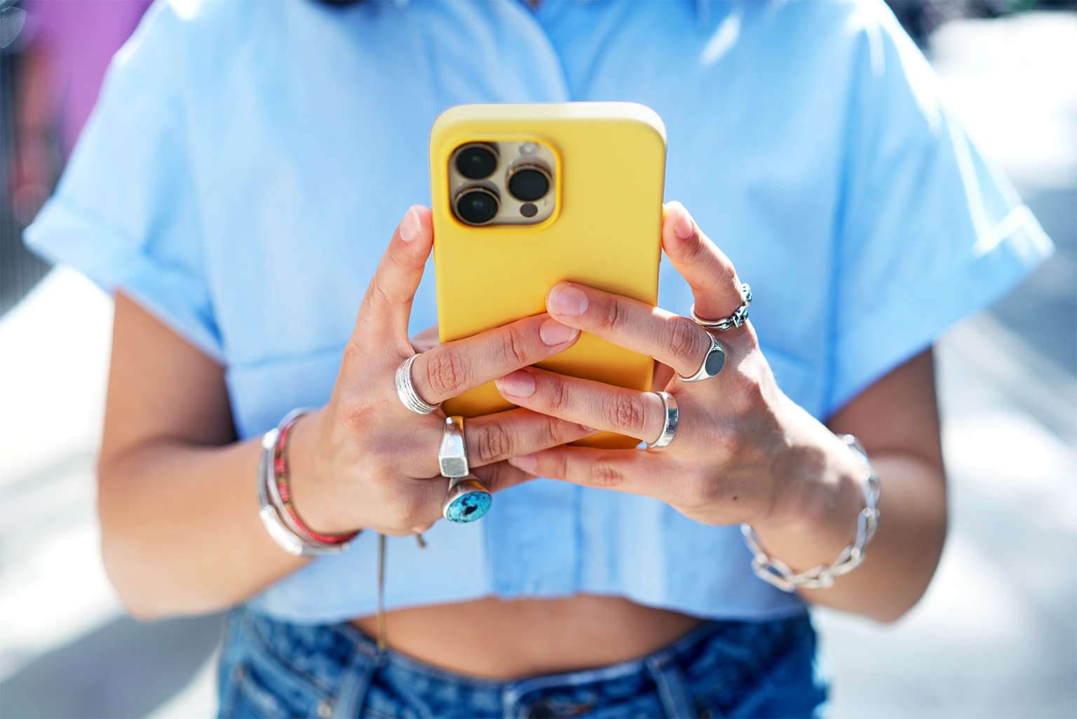 Close up of a person holding a smart phone up in front of them while typing on it.