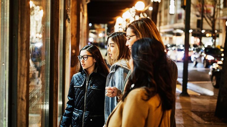 Two mature women and teenage daughters window shopping during holidays