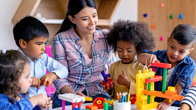 Pre-K teacher with children playing with building blocks