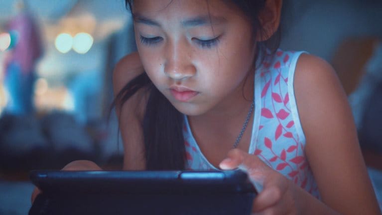 Close-up of little girl using tablet at night