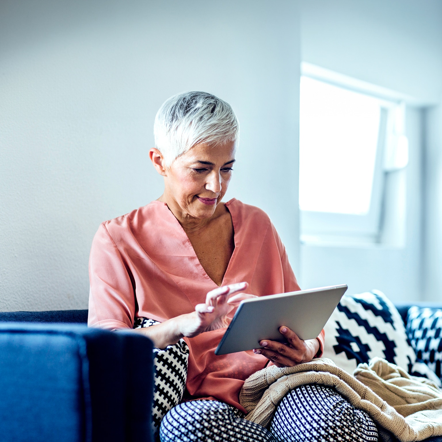 Older Caucasian woman using digital tablet on sofa