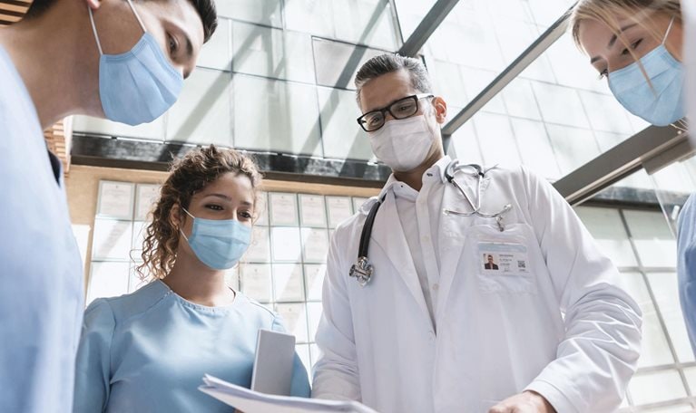 Group of doctors talking at the hospital and wearing facemasks