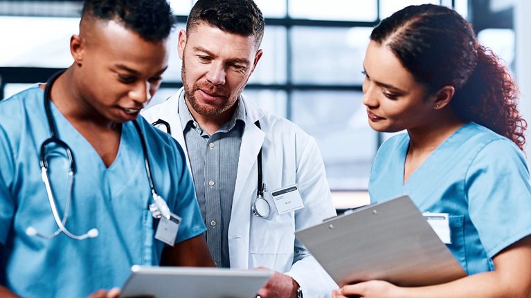 A group of medical practitioners using a digital tablet together in a hospital