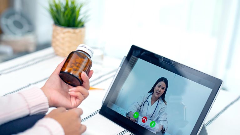 A young woman engaged in a video conference with her doctor. 