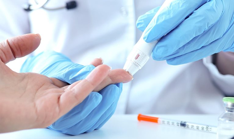 Doctor with gloves piercing patients finger with lancet closeup - stock photo