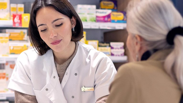 A female pharmacist discussing a prescription with an elderly lady customer at the service counter in a pharmacy