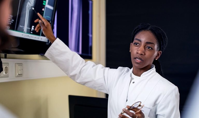 Female surgeon discussing patient's scan and diagnosis with colleagues