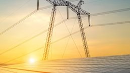 High voltage pylons with electric power lines transferring electricity from solar photovoltaic sells at sunrise. Production of sustainable energy concept. - stock photo