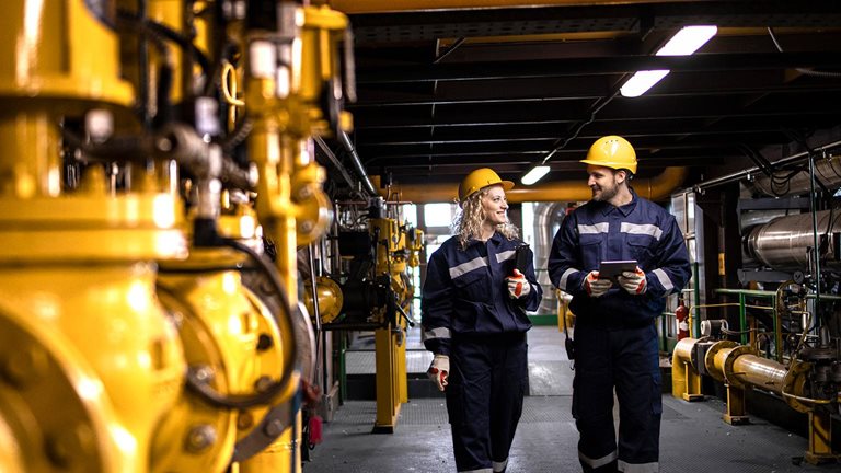 Oil and gas refinery production. Factory workers in safety equipment walking by gas pipes and checking distribution and consumption. - stock photo