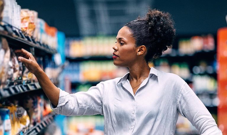 Woman Shopping in Supermarket Aisle Searching for Products