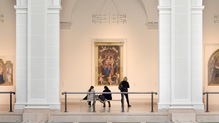 People view artwork along a hallway framed by three large arches in Brooklyn Museum’s Beaux-Arts Court.