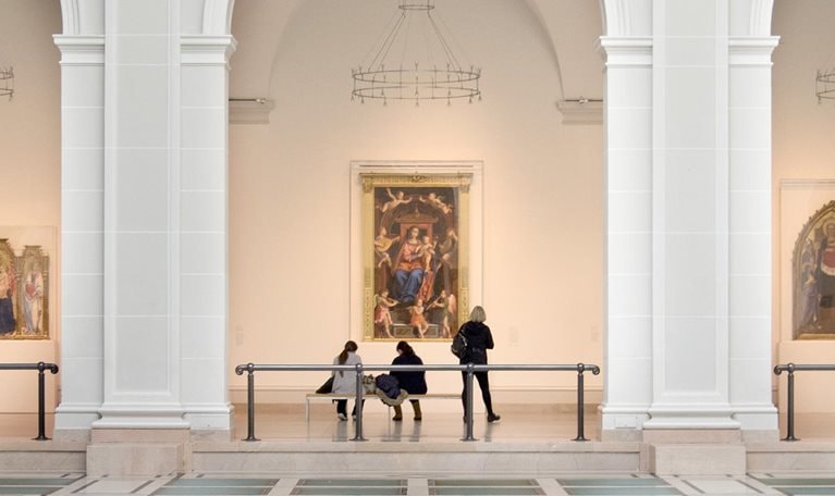 People view artwork along a hallway framed by three large arches in Brooklyn Museum’s Beaux-Arts Court.