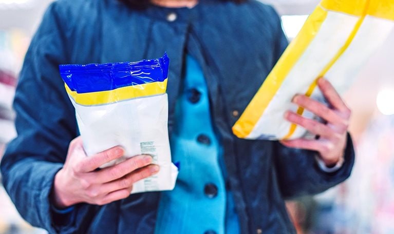Image of a person reading the labels and comparing products in a store.