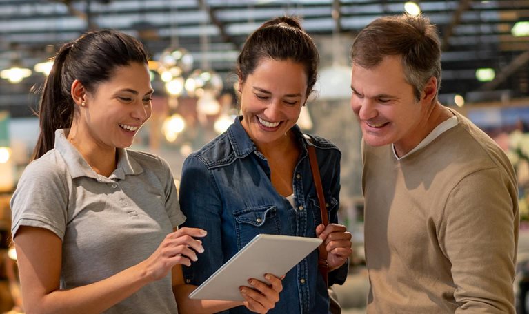 Middle aged couple in store being shown inventory on tablet by younger employee