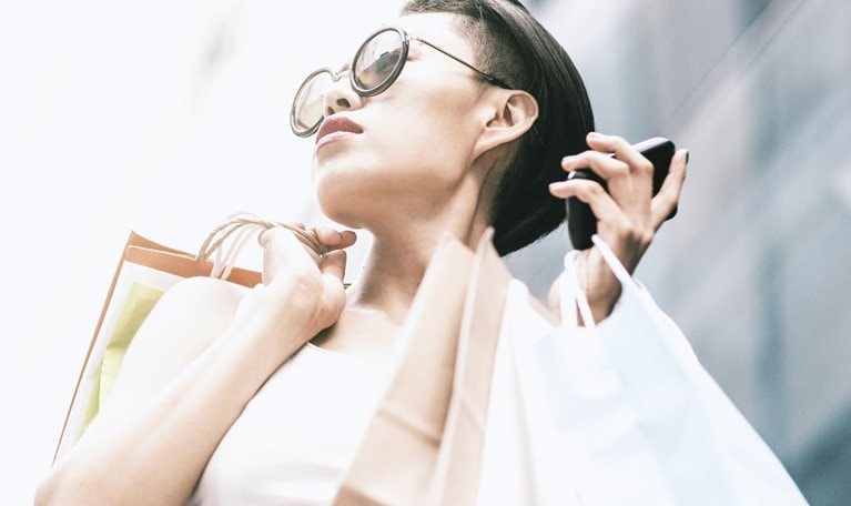 Woman using phone while shopping - stock photo