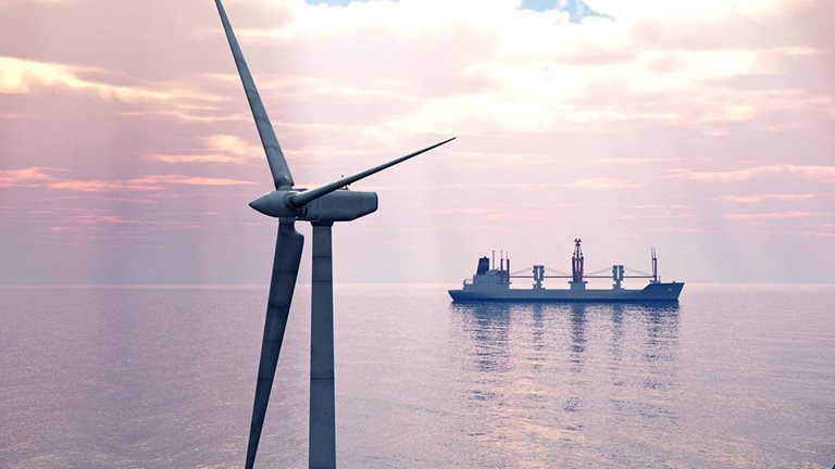 Close-up of offshore wind turbines with a cargo ship in the distance