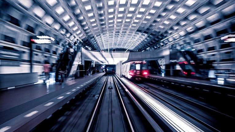 Blurred image of train car leaving the inside of a metro station.