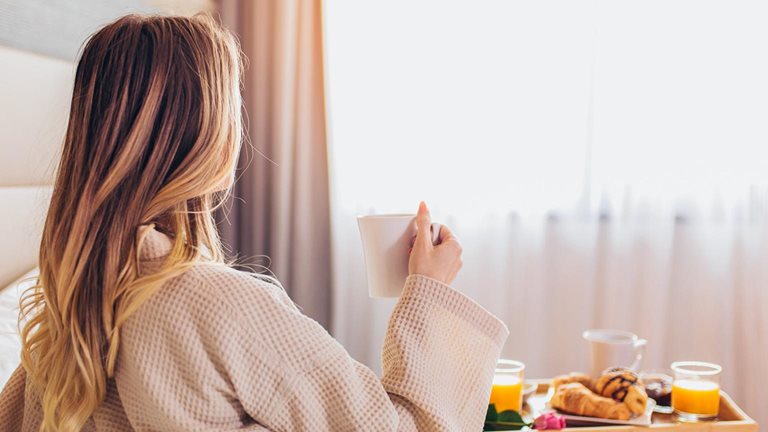 Woman laying and enjoying, breakfast in bed