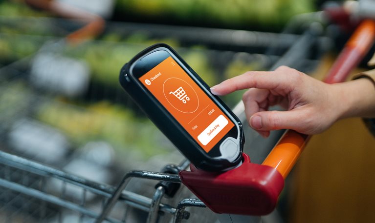 Close up shot of female hand touching a digital device on the shopping cart in supermarket. Smart shopping makes grocery shopping convenient. Contactless payment concept.