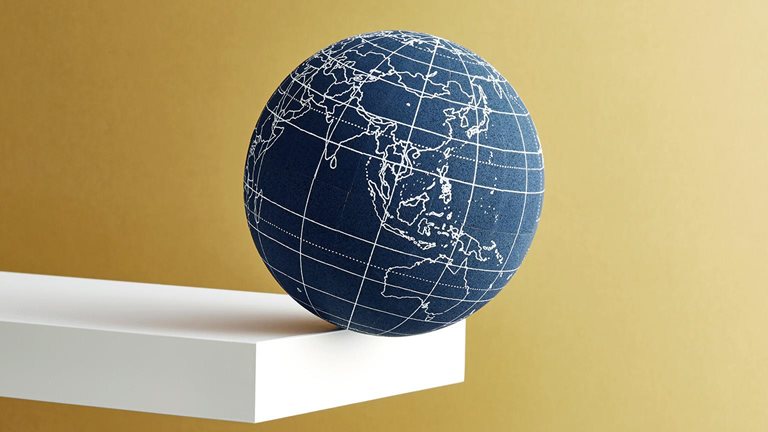 Image of a globe balanced on the edge of a shelf.