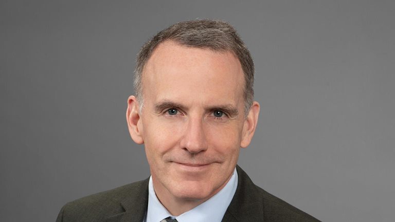 Portrait of Ed Glaeser in a dark gray suit against a seamless gray backdrop.