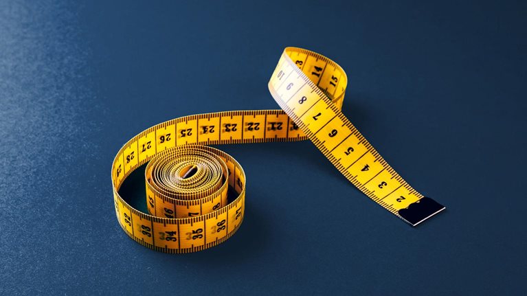 Yellow tailor's tape measure on a dark blue board.