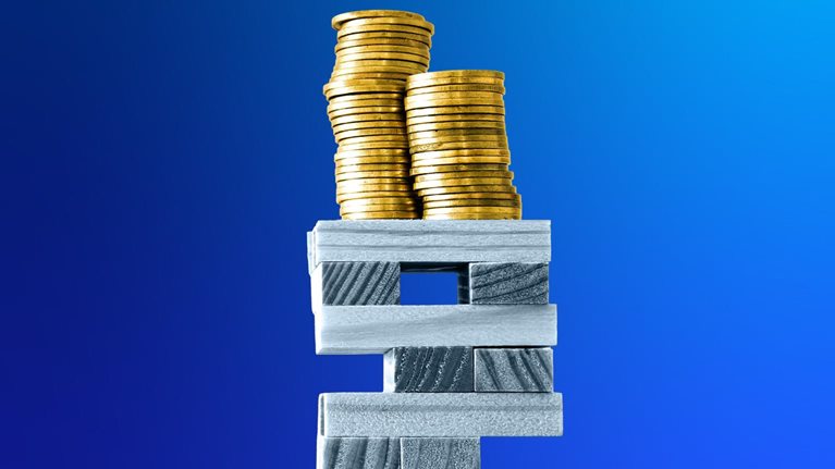 Stacks of gold coins rest on top of a precarious tower made of wooden rectangular blocks against a deep blue background.