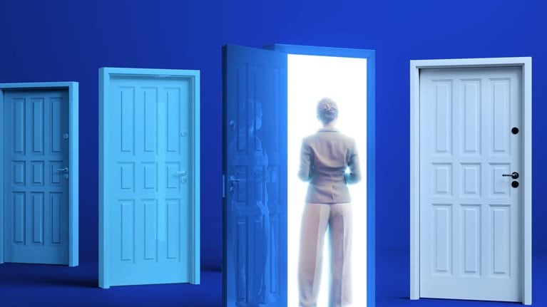 A woman in business attire stands before a brightly lit doorway. Several other closed doors of varying shades of blue are to her left and right.